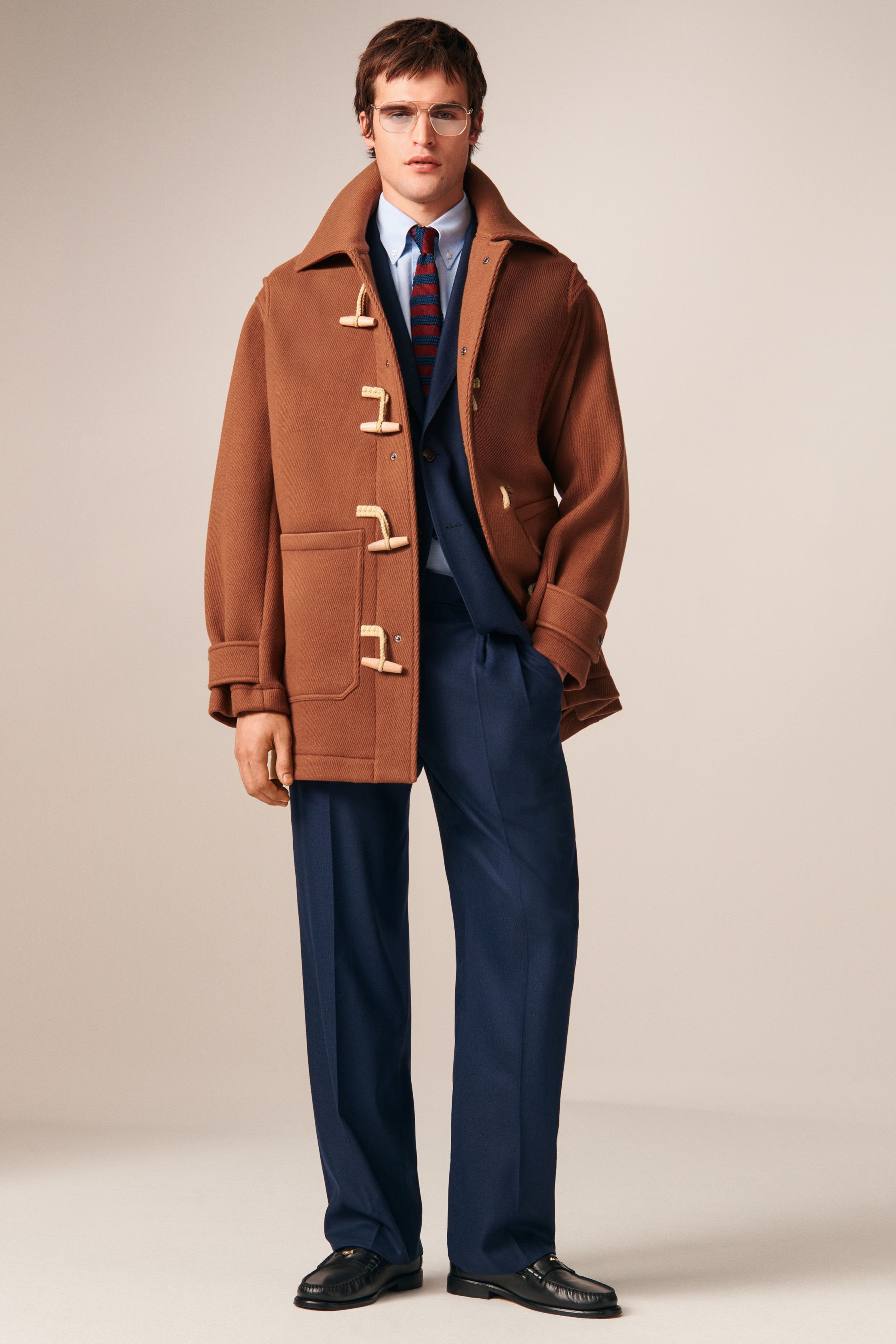 Tommy Hilfiger 26FW 男装回到品牌最擅长的美式学院与都市绅士语境。条纹针织、飞行夹克、羊羔毛外套与双排扣大衣共同勾勒出成熟却不老派的美式精英形象。色彩以海军蓝、酒红、驼色为核心，强化可靠、易穿的商业属性。系列不追求先锋表达，而是精准回应全球市场对“经典升级版”的现实需求-顽石频道趋势研究